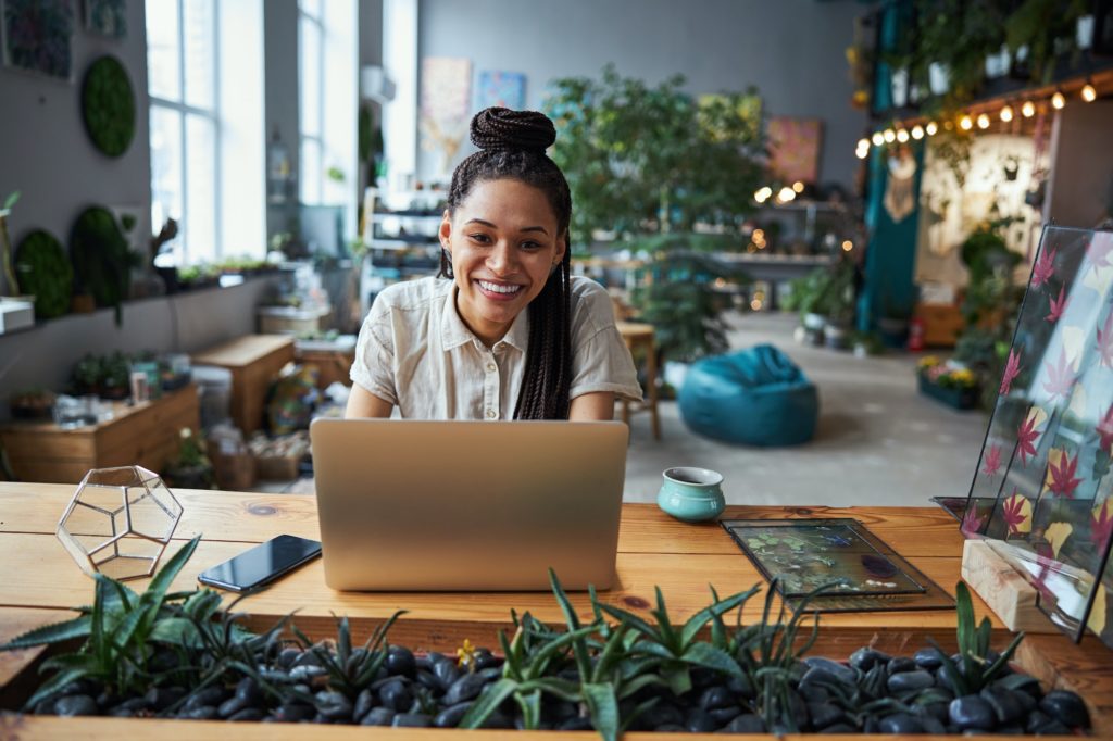 Florist with cornrows sitting at a laptop in the workshop