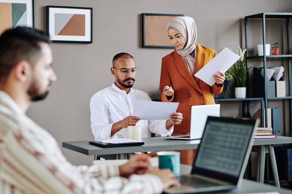 Young Muslim female and male economists discussing financial papers